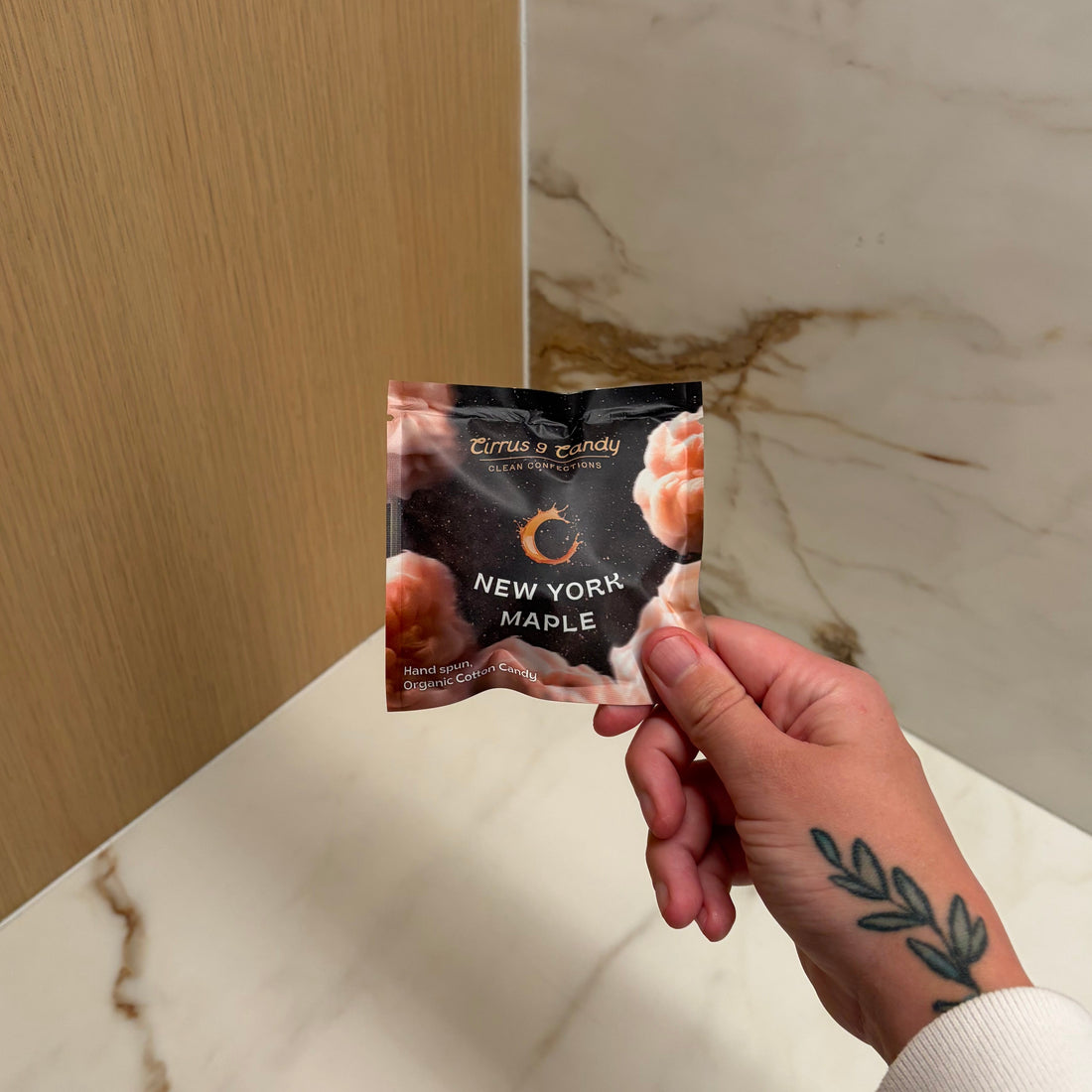 Hand holding a snack packet over a marble countertop