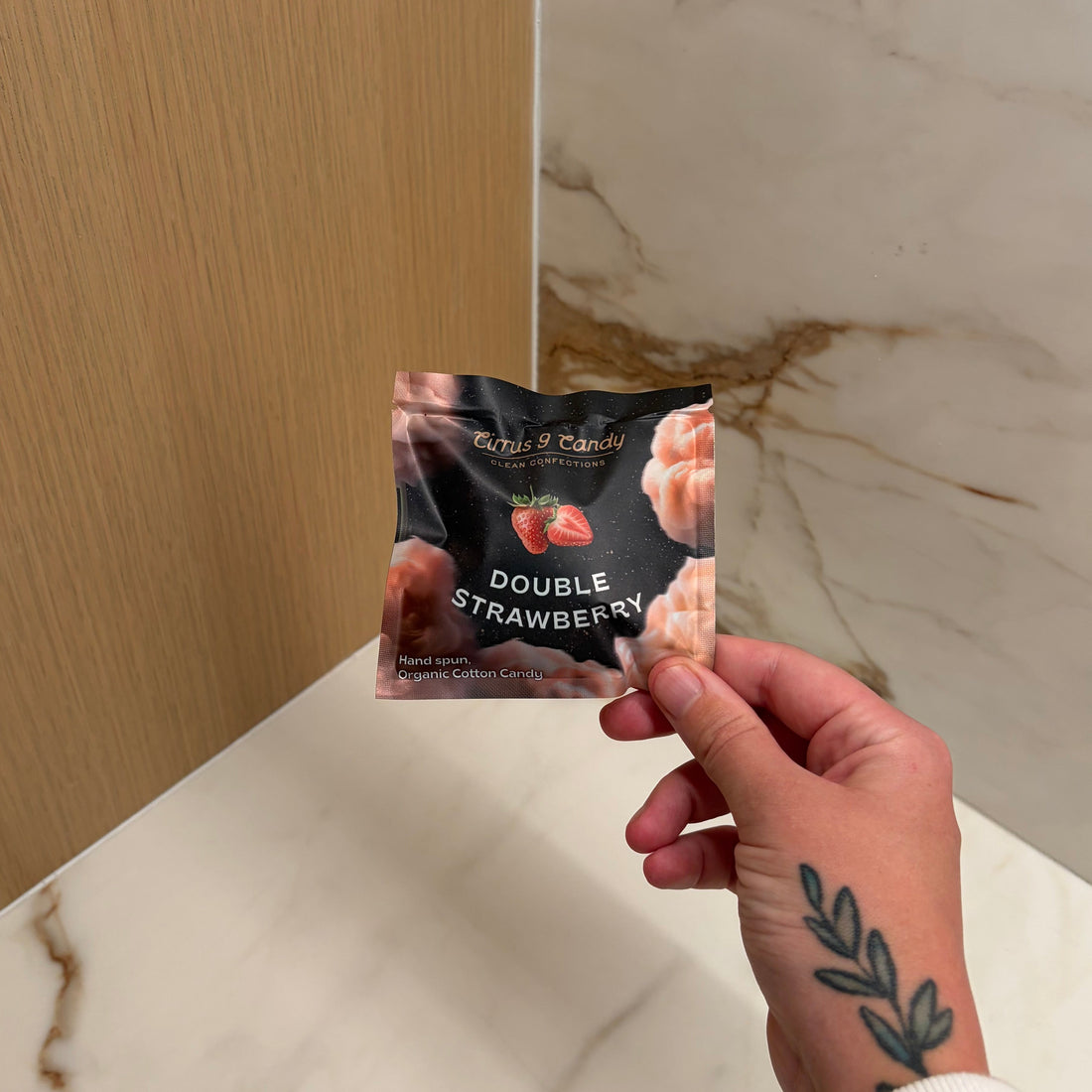 Hand holding a product package against a marble and wood surface