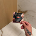 Hand holding a product package against a marble and wood surface